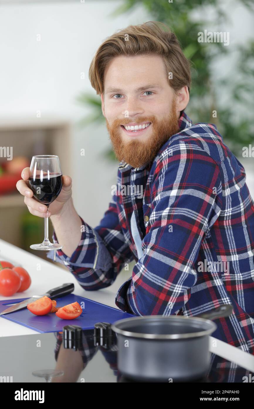 man drinking a glass of wine while cooking Stock Photo Alamy
