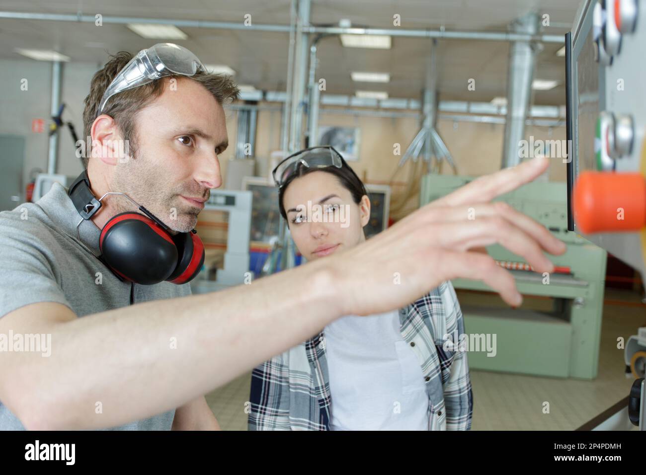 engineer training female apprentice on cnc machine Stock Photo
