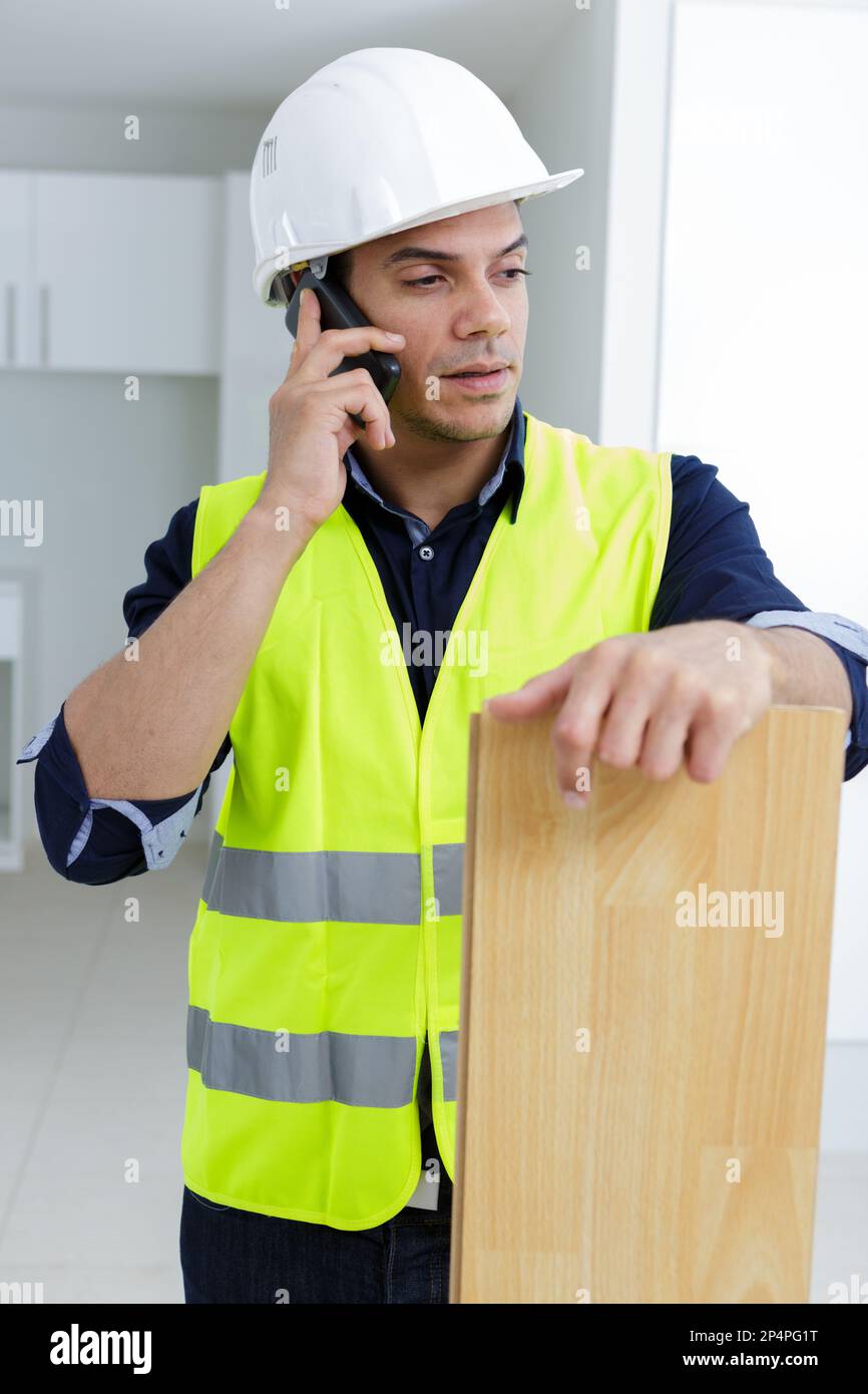builder on phone holding plank Stock Photo