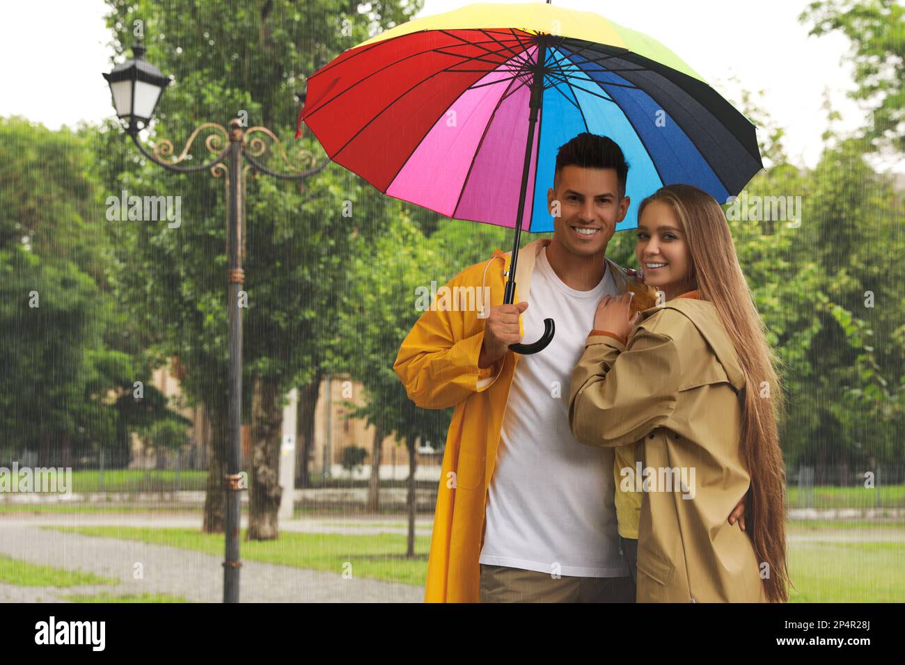 Lovely couple with umbrella walking under rain in park Stock Photo - Alamy