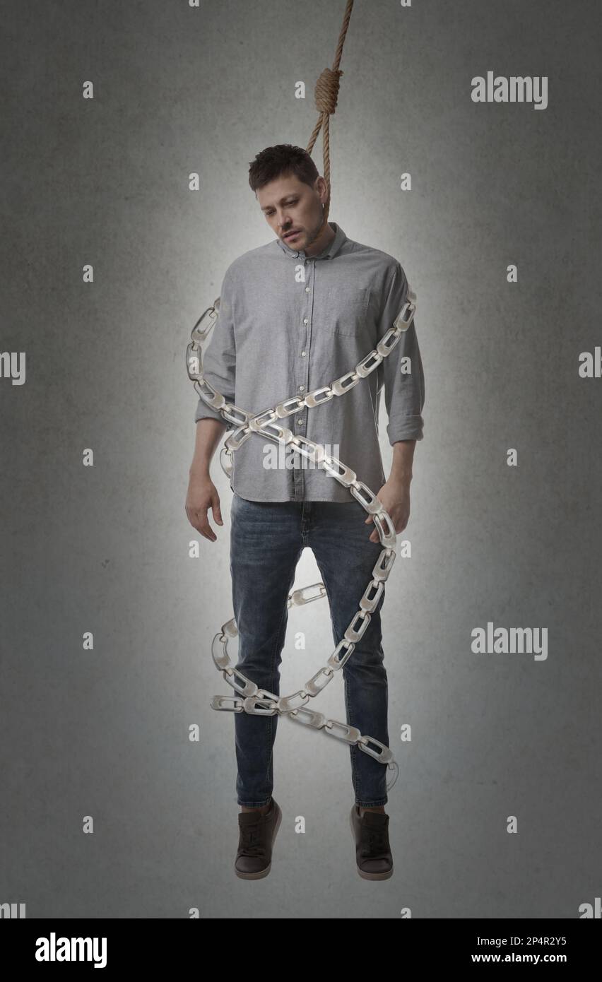Depressed man with rope noose on neck and metal chains around him