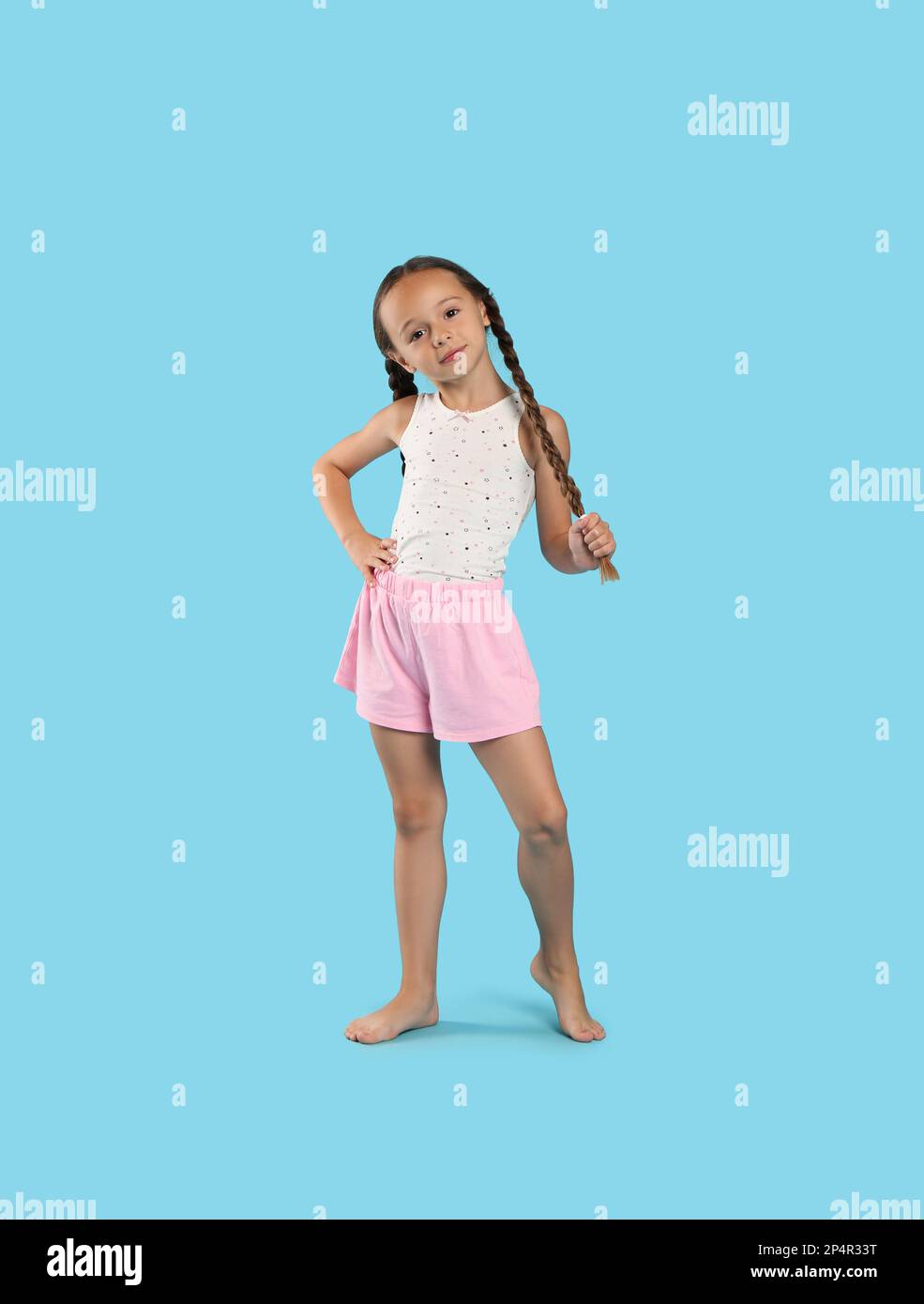 Cute girl wearing pajamas on light blue background Stock Photo - Alamy