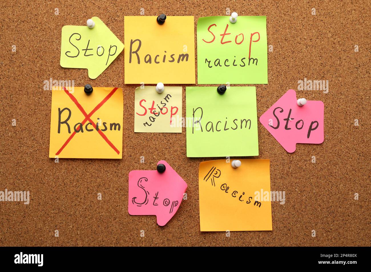 Paper notes with phrase Stop Racism pinned to cork board Stock Photo