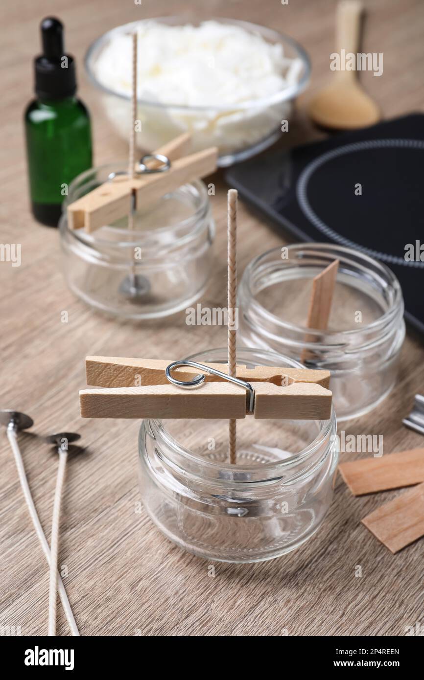 Glass jars with wicks and clothespins as stabilizers on wooden table ...