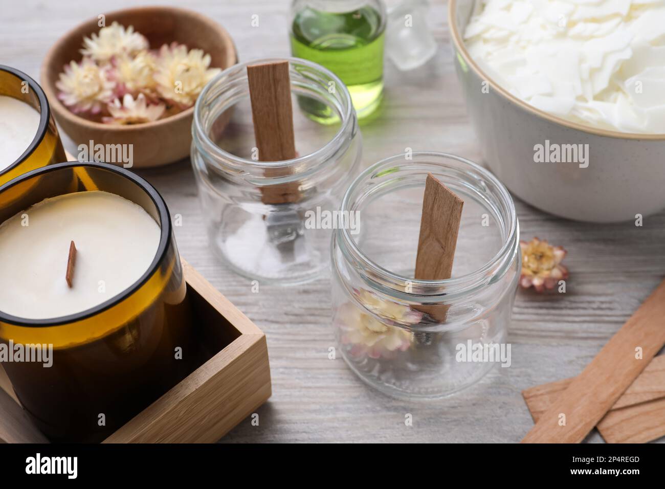 Glass jars with wooden wicks on light table. Making homemade candles ...