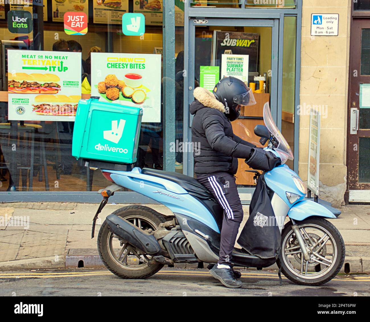 Glasgow, Scotland, UK 6th March, 2023. UK Weather: Deliveroo motorcyclist Sunny start saw happier locals as the streets filled in the spring weather before the forecast return of winter.Byres road in the sun.  Credit Gerard Ferry/Alamy Live News Stock Photo