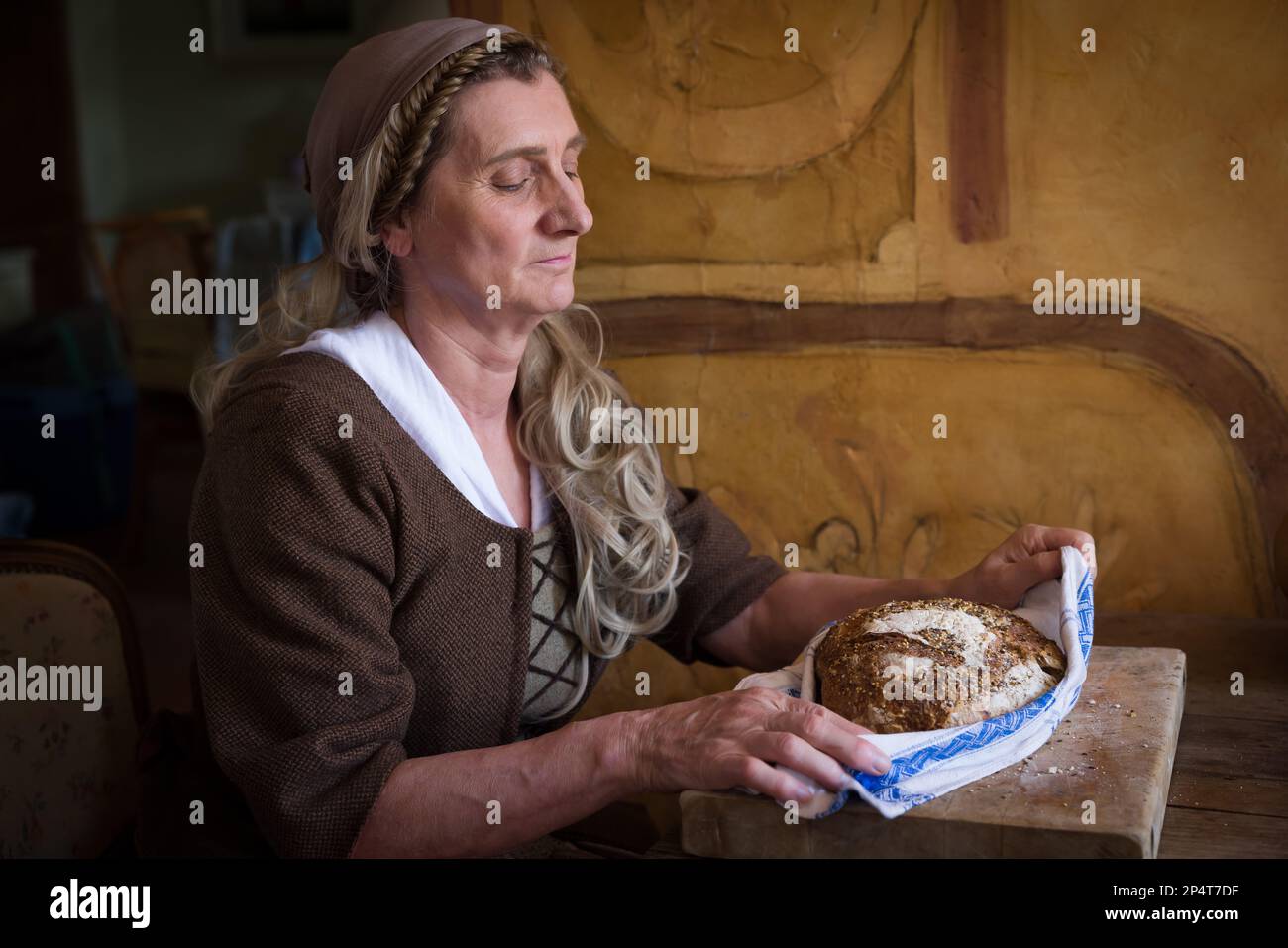 Woman in authentic peasant renaissance costume holding bread. Stock Photo