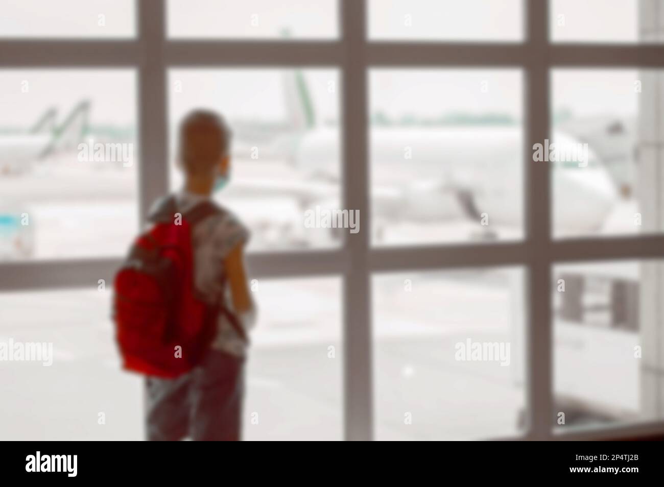 Blurred back view of a boy with red backpack in the waiting room at the airport Stock Photo