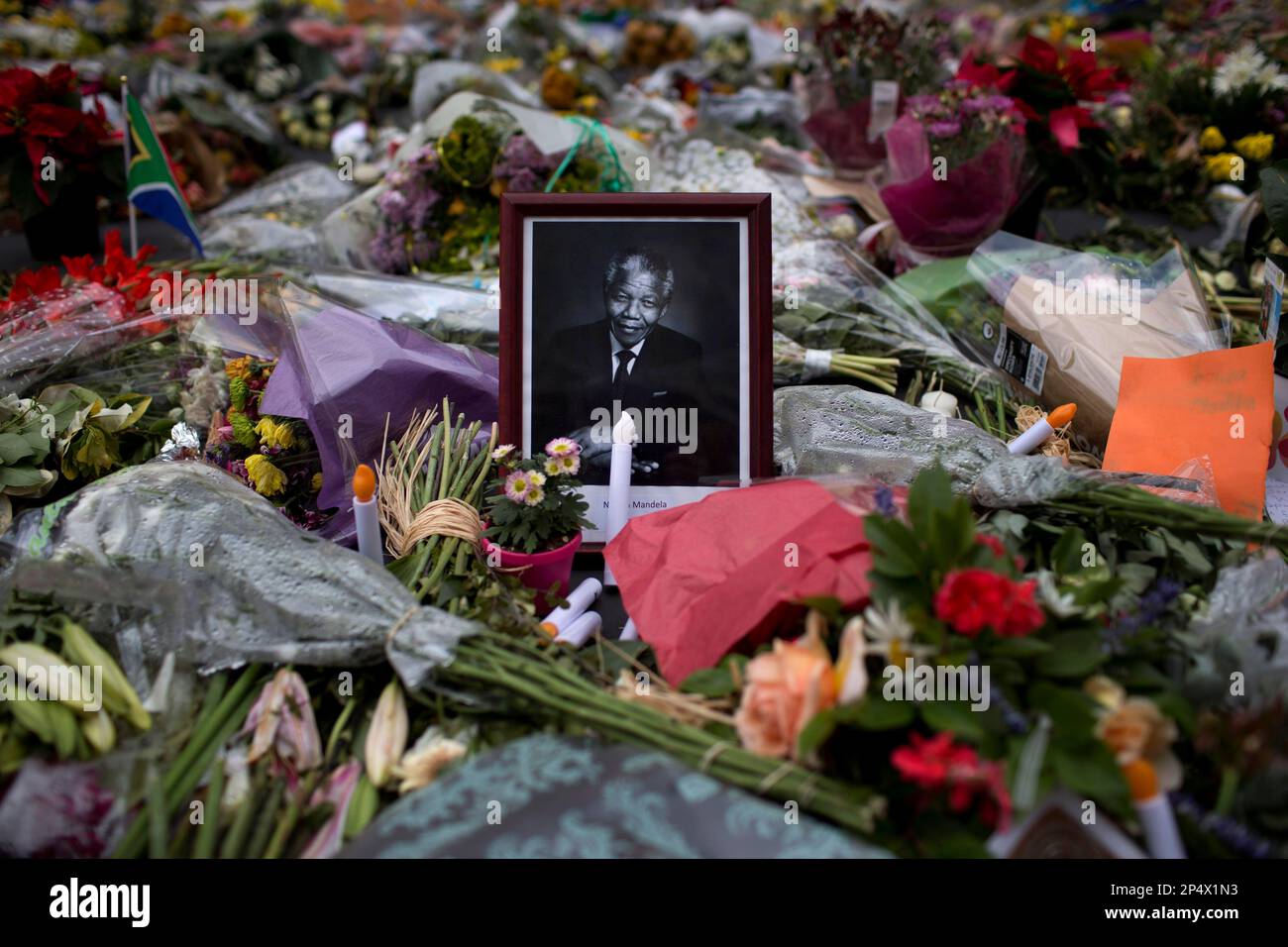 A picture of late President Nelson Mandela is surrounded of flowers, candles and condolence