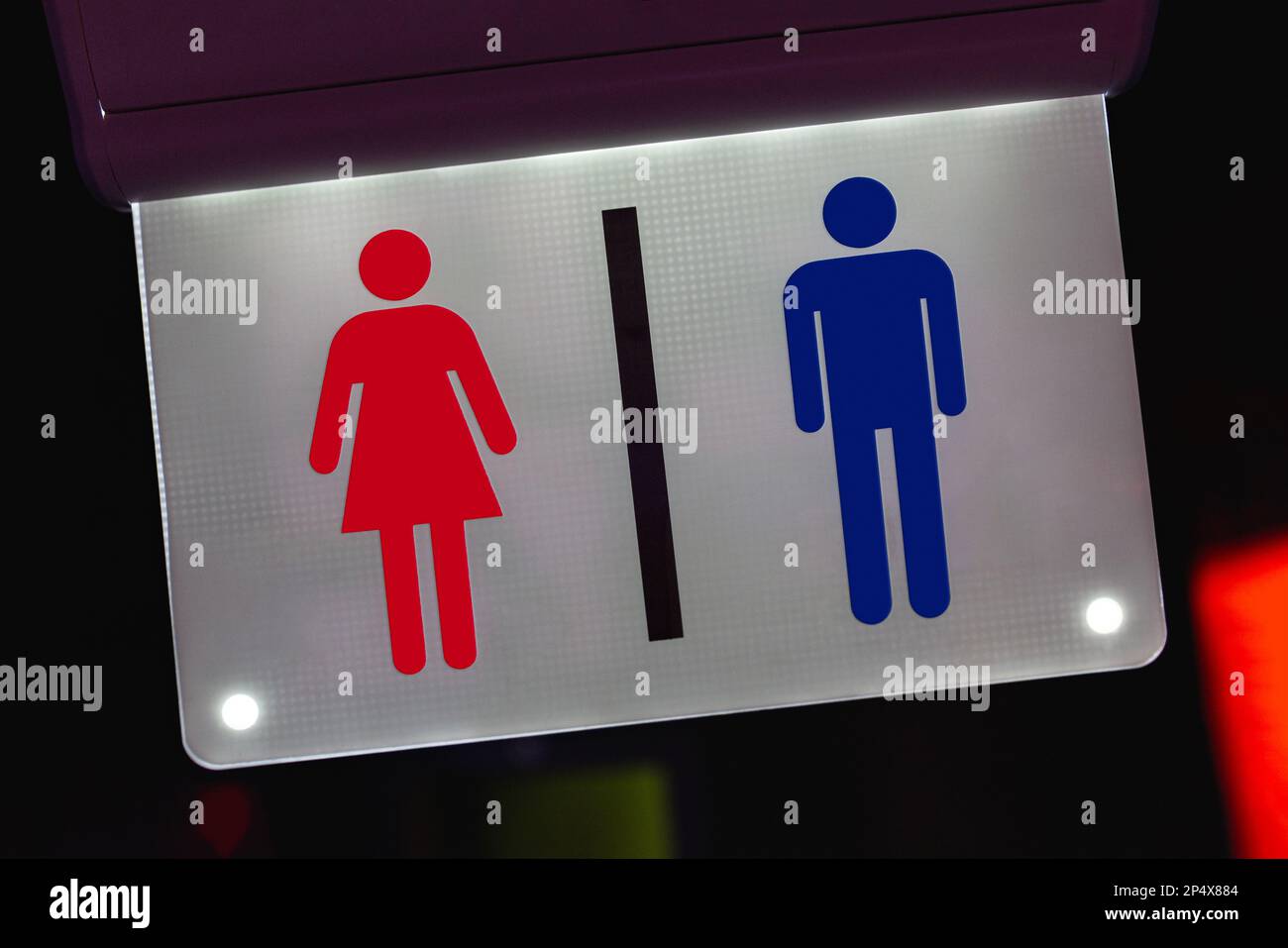 Close-up of an illuminated sign with icons of male and female figures indicating the Toilets. Stock Photo