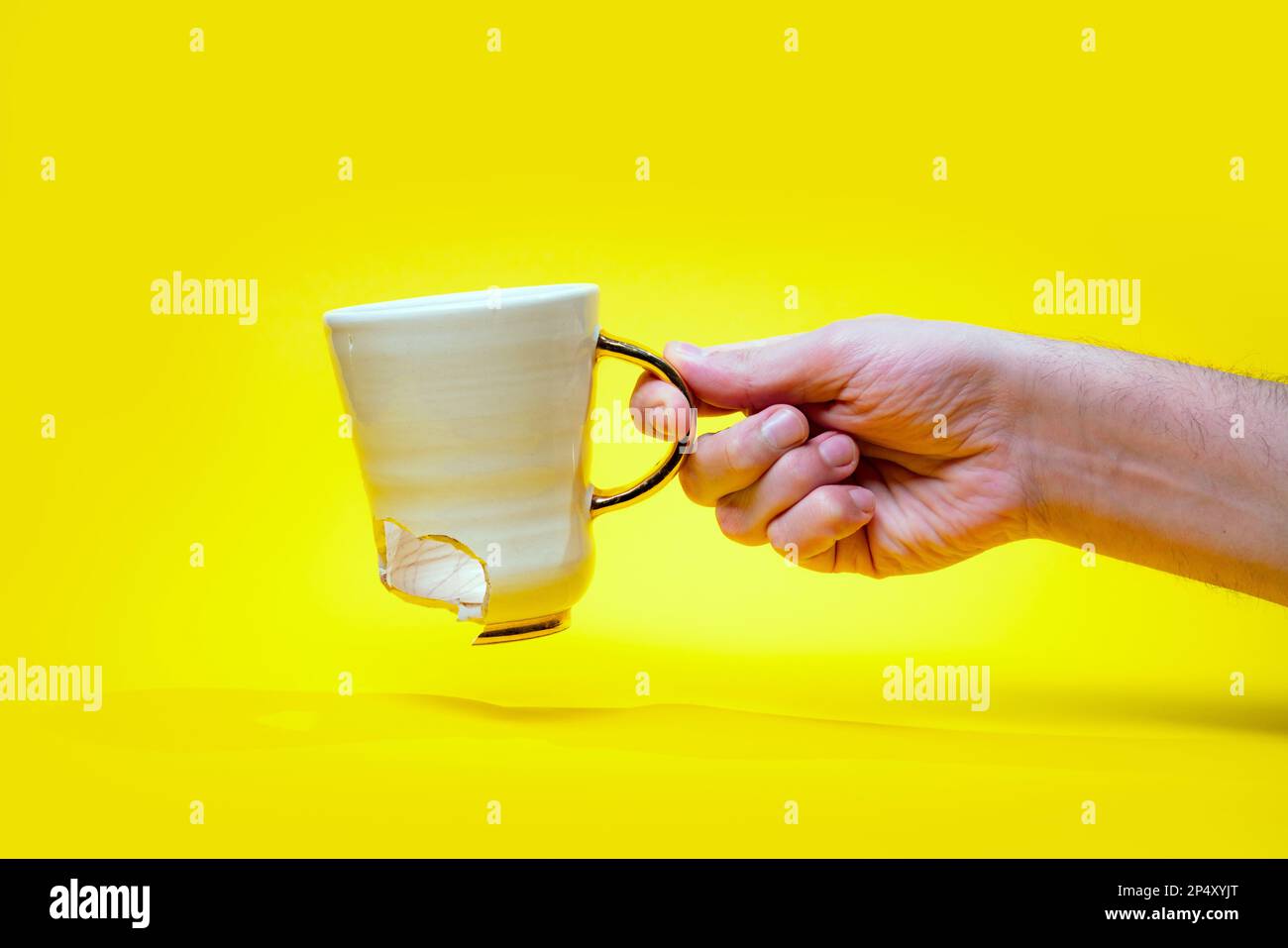 Man holding broken tea cup isolated on yellow background. Close up of