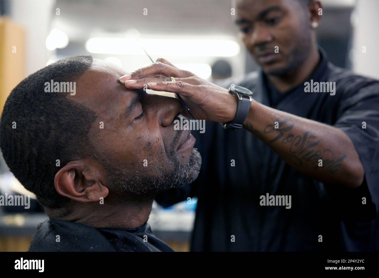 Lindsay Cuba, 53, gets a shave from Tromondae Murphy, 36, on Friday, Nov.  22, 2013, at Salon Sebastian in Flint, Mich. Cuba has been visiting the  same barber shop for 11 years. (