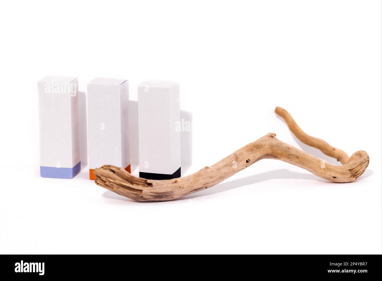 Mockup of three cardboard rectangular boxes for cosmetics. Branch or tree root on the background. White backrop. Free spase for text. Stock Photo