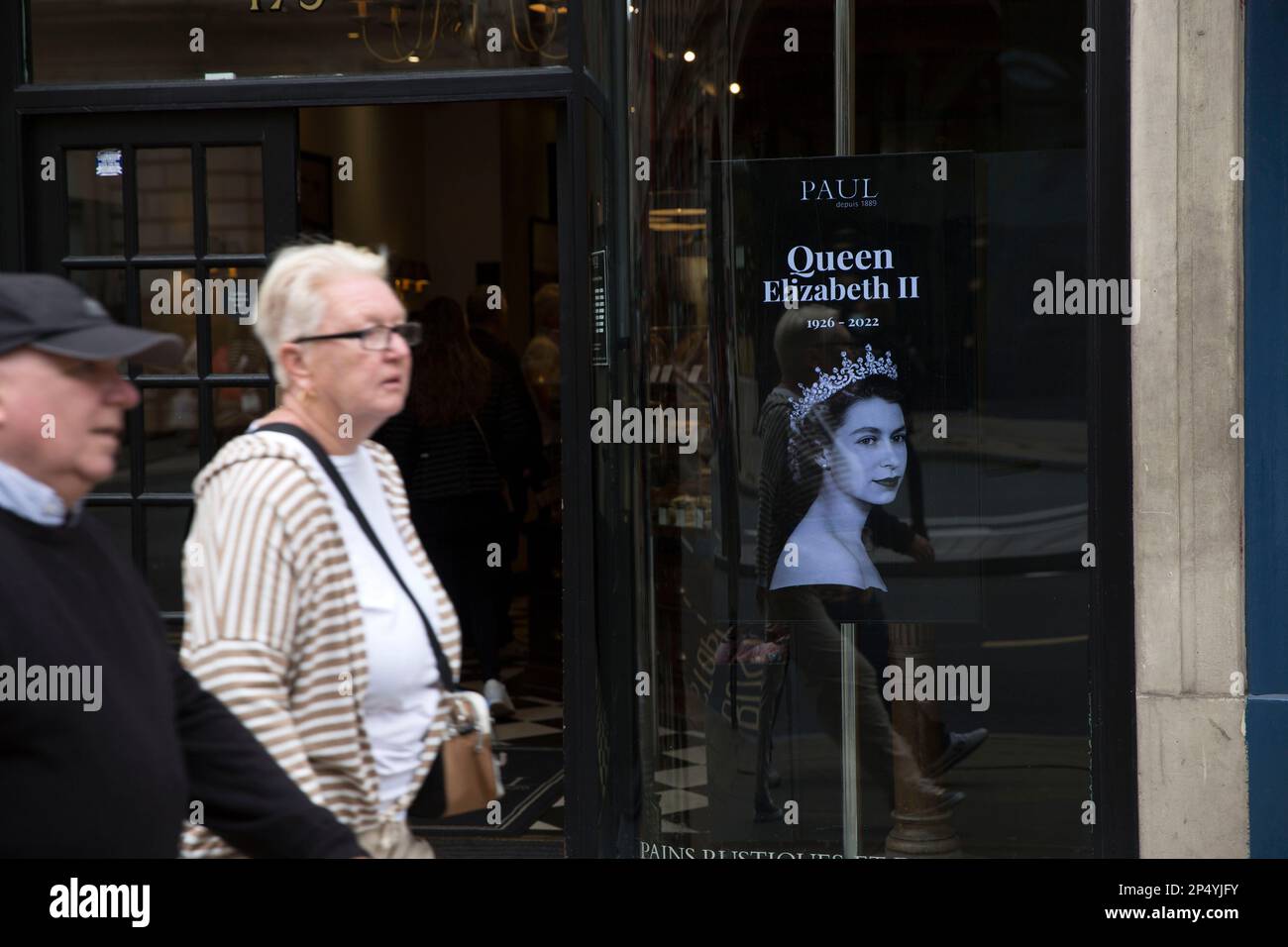 A portrait of the late Queen Elizabeth II is seen as mourners gather to pay their respects in central London, on the day of her funeral. Stock Photo
