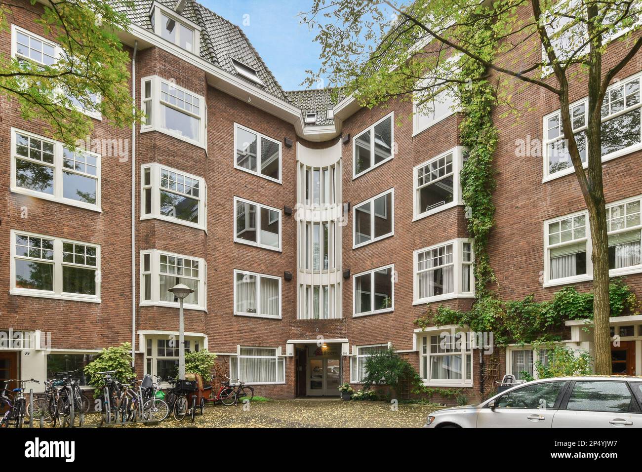 an apartment building with bicycles parked in the driveway and cars ...