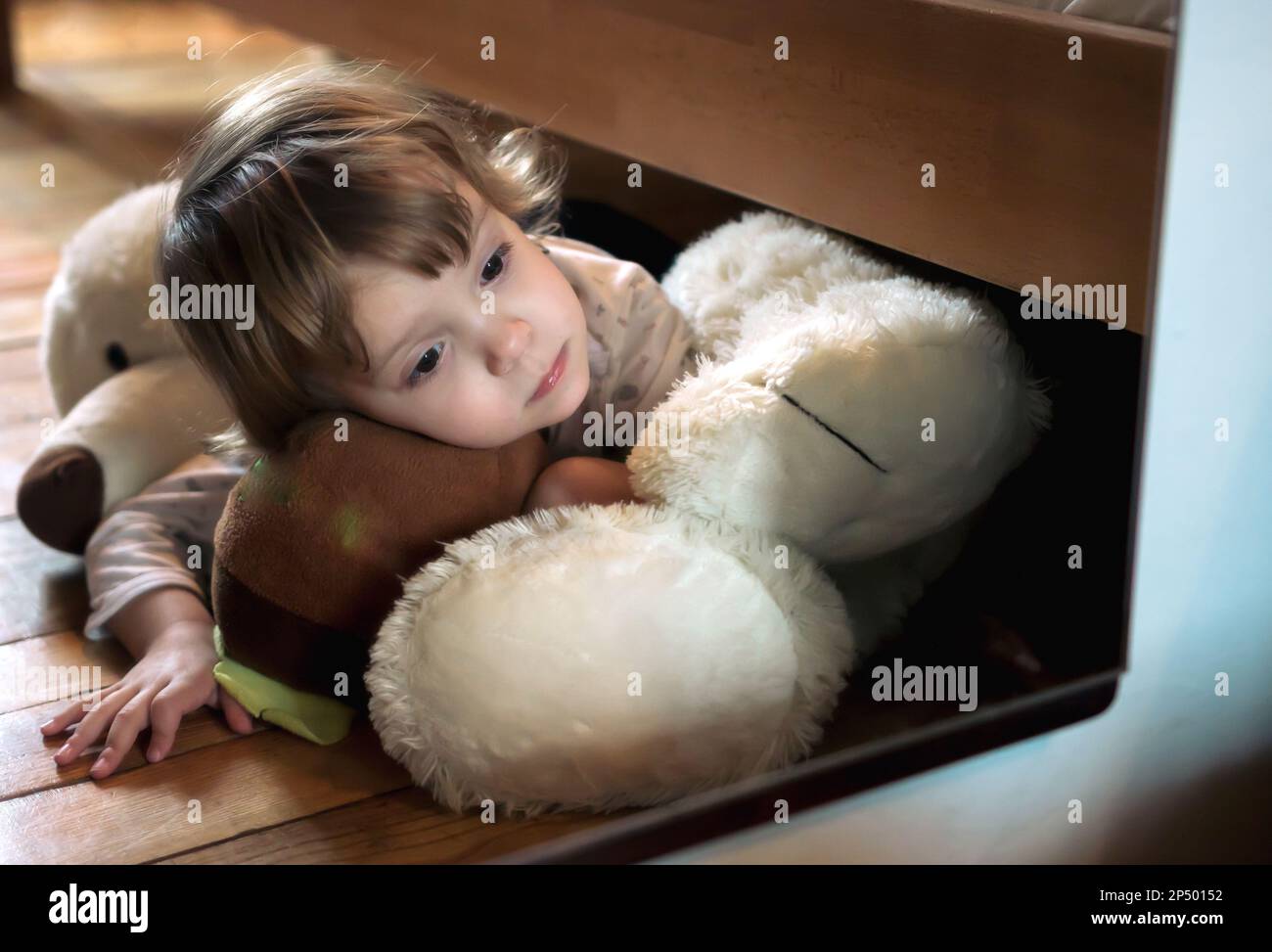 Girl looking herself in a mirror while lying on her teddy bear at home