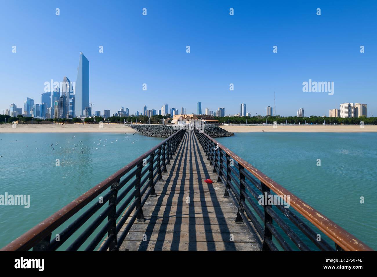 Kuwait City skyiline seen from the Kuwait Tower fishing ramp, a public pier for fishing. Dasman beach and skycrapers. Stock Photo