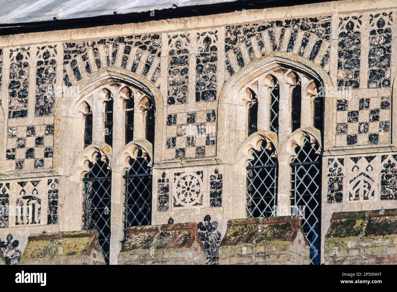 UK medieval church exterior, detail of the flushwork and chequered flint decoration around the clerestory windows of Woolpit Church in Suffolk, UK Stock Photo