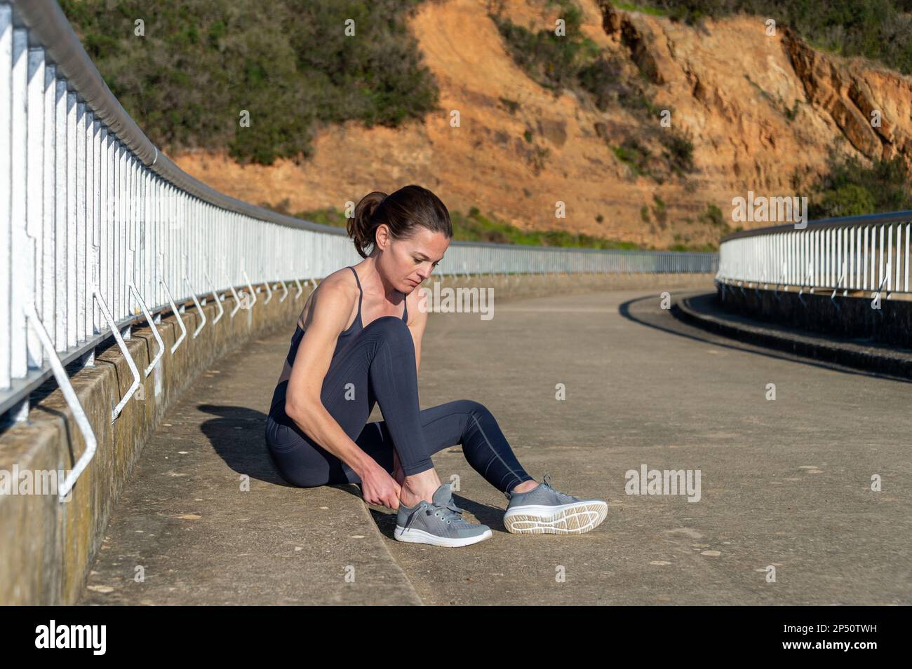 Sporty fit woman puttin on her running shoes outside. Preperation for running and jogging. Stock Photo