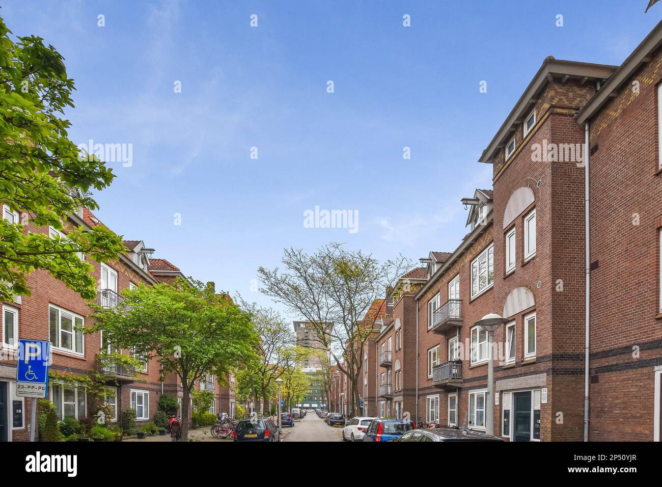a city street with cars parked on both sides and people walking down ...
