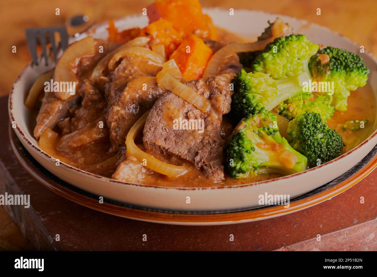 Liver and onion dinner with sweet potatoes and vegetables covered in a beef gravy. Stock Photo