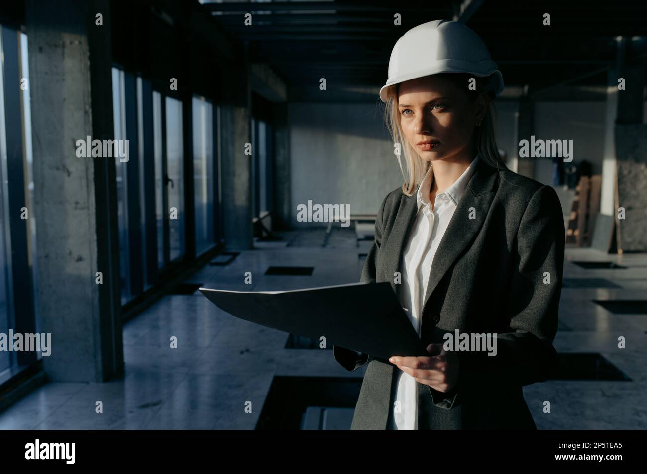 Portrait of a businesswoman, an engineer at a construction site. Female architect with blueprint. Stock Photo