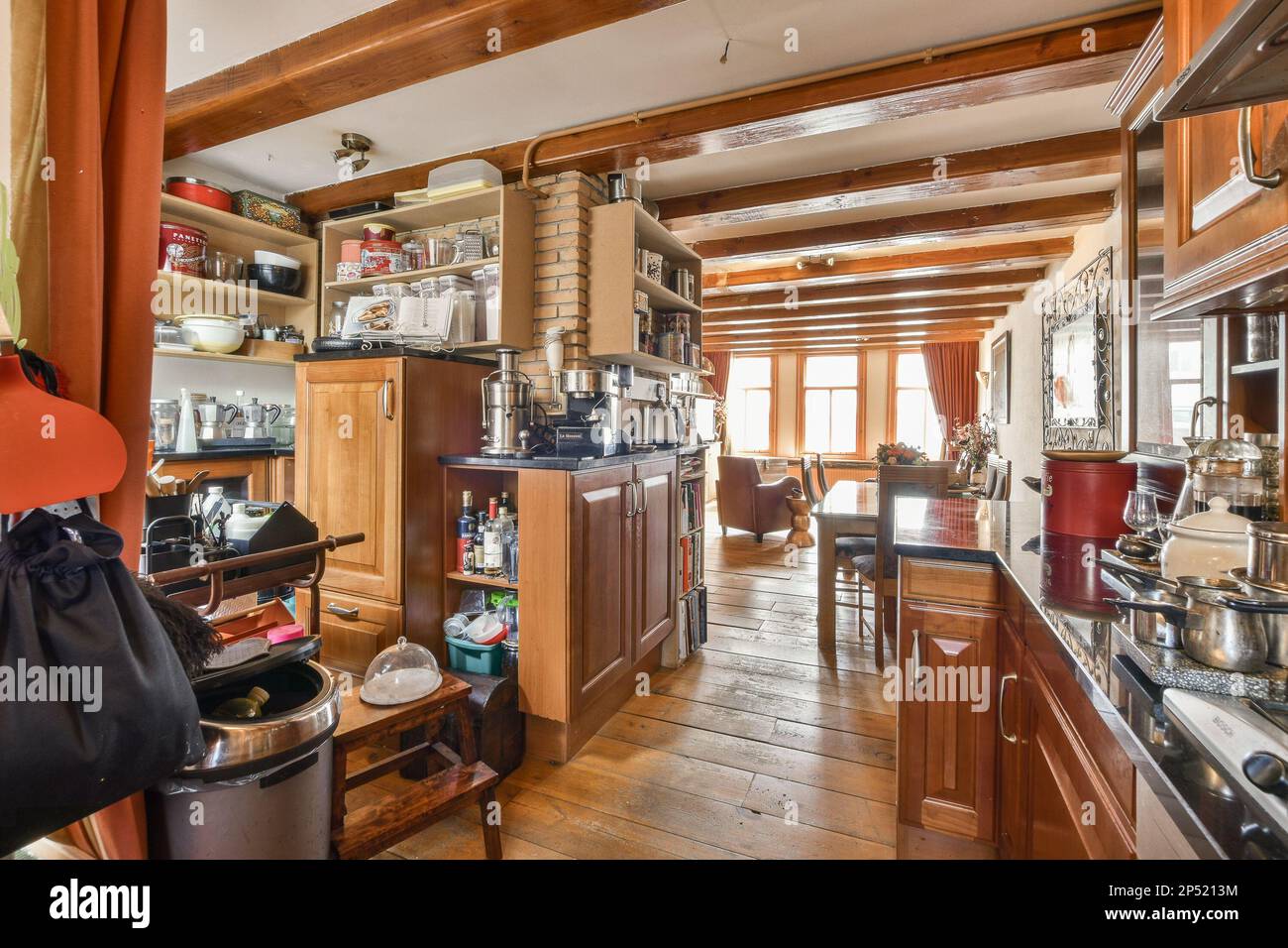 Amsterdam, Netherlands - 10 April, 2021: a kitchen and dining area in an old house with wood floors, wooden cabinets, stainless appliances and stoves Stock Photo