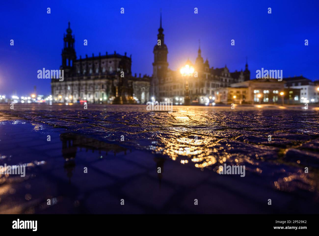 Dresden, Germany. 06th Mar, 2023. Lights of the city lighting reflect in the evening after a rain shower on the wet cobblestones on Theaterplatz in front of the Hofkirche (l-r), the Hausmannsturm, the Residenzschloss and the Schinkelwache. Credit: Robert Michael/dpa/Alamy Live News Stock Photo