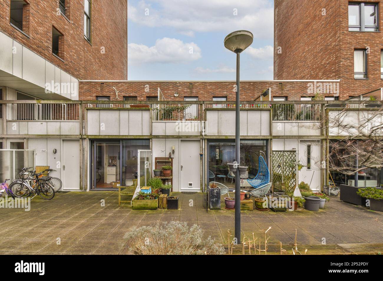 Amsterdam, Netherlands - 10 April, 2021: an apartment complex with bikes parked in the yard and two balks on the other side of the building, Stock Photo