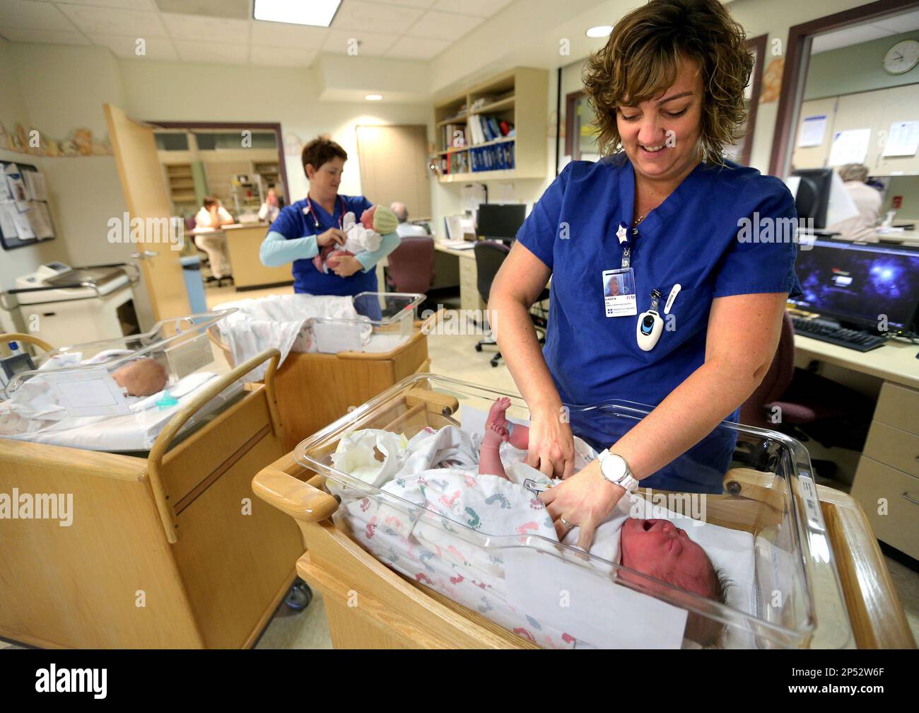In this Oct. 9, 2013 photo, Karen Soppe, R.N., right, changes the diaper on  newborn, Ayden James Wolter, as Laura Knabel, R.N., calms anoth