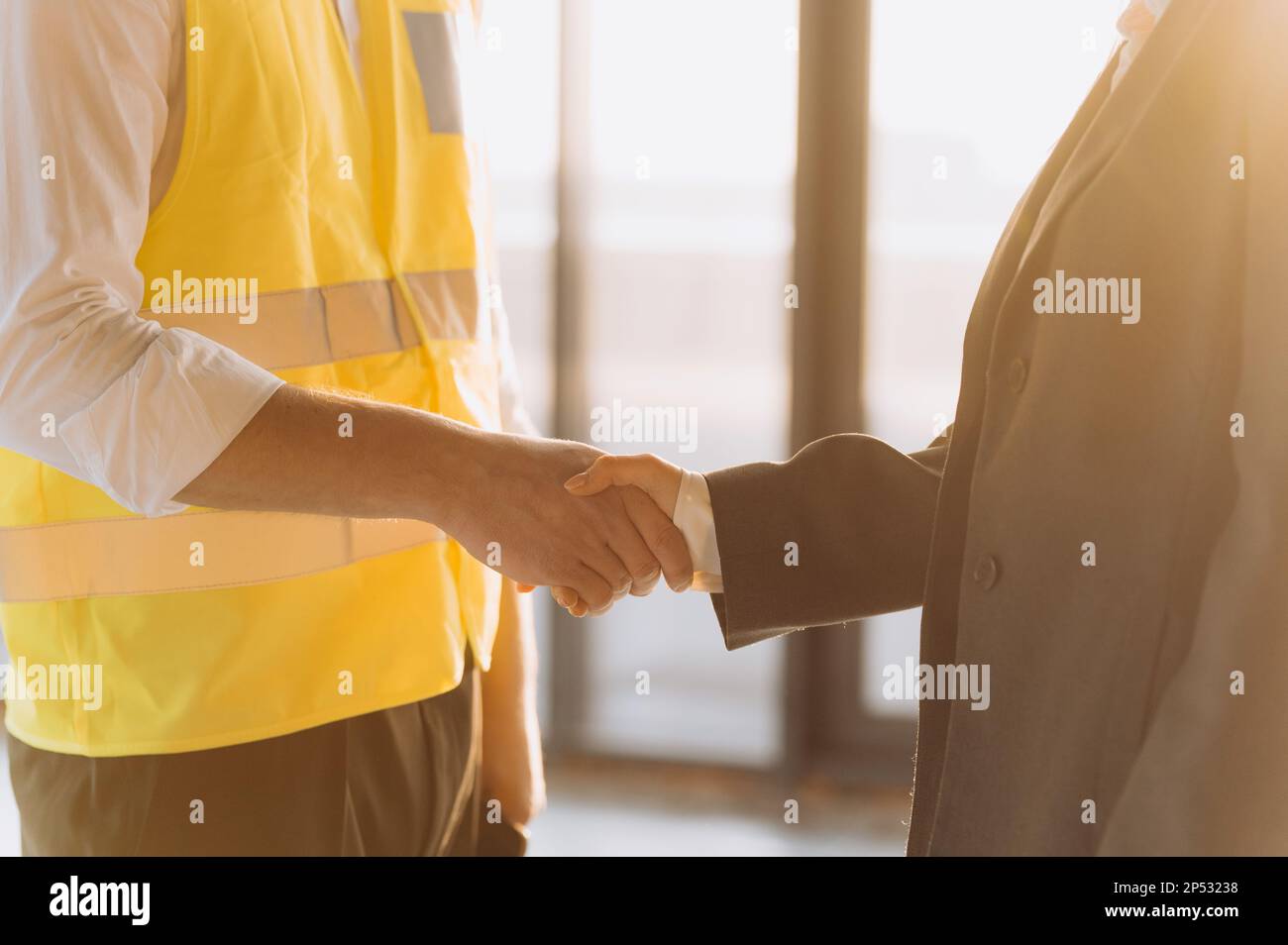 Close up engineer shake hand on site construction. handshake at sunset Stock Photo