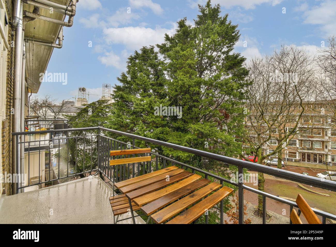 some wooden benches on a balcony with trees and buildings in the background, taken from an apartment's balcony Stock Photo
