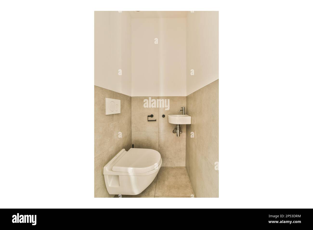 a white toilet in the corner of a bathroom with beige tiles on the walls and floor, there is an image of a wall Stock Photo