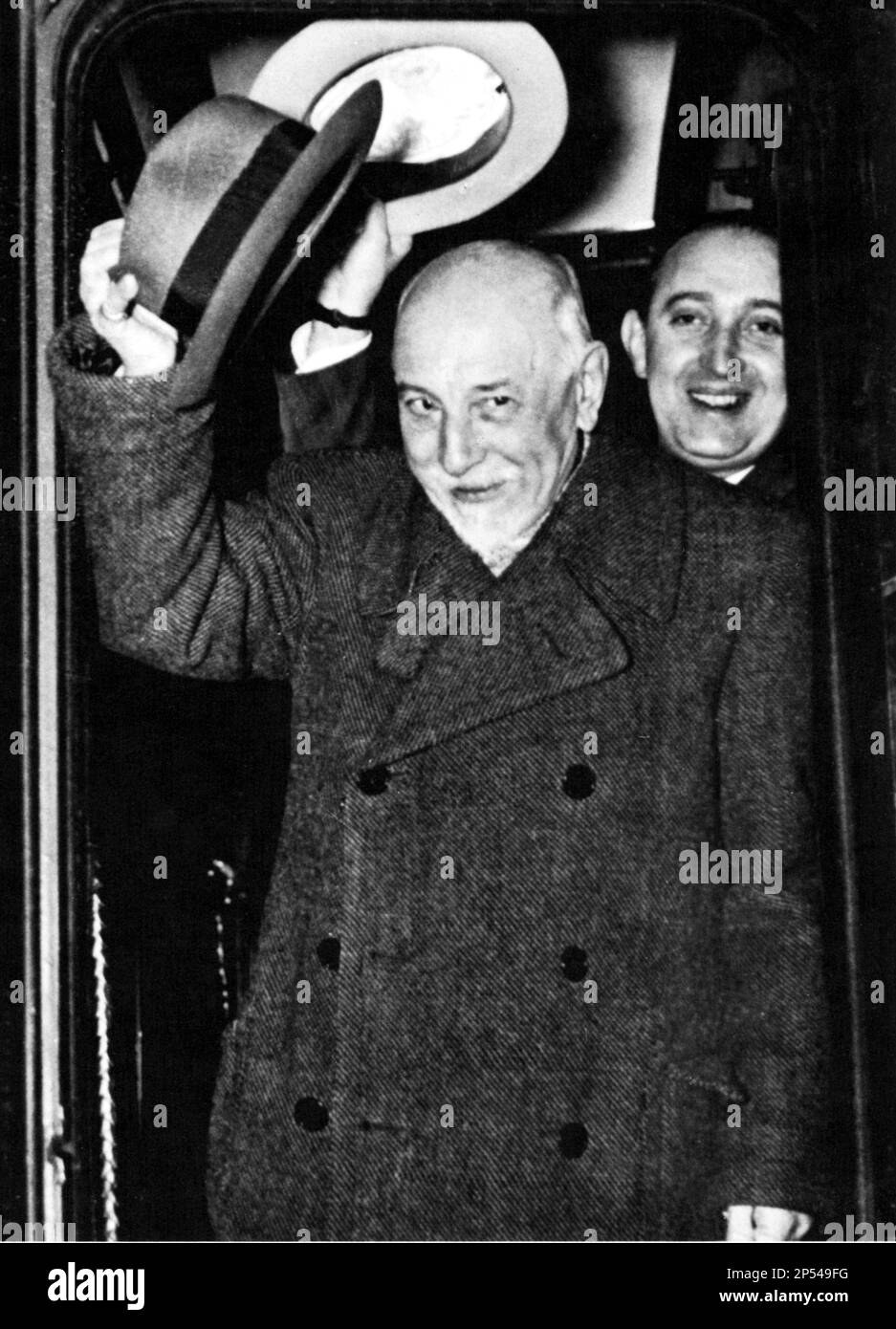 1934 , december , Stockholm , Sweden   : The italian  dramaturgist LUIGI PIRANDELLO ( 1867 - 1936 ) arrive in Sweden to receive the NOBEL PRIZE for LITERATURE  . With him his agent by Mondadori edition house  - TEATRO - THEATER - THEATRE - DRAMMATURGO - dramatist - scrittore - writer - letterato - letteratura - playwriter - play-writer - play writer  - commediografo - portrait - ritratto  - hat - cappello - saluto - salute - smile - sorriso - coat - cappotto - PREMIO NOBEL  - LETTERATURA - LITERATURE ----  Archivio GBB Stock Photo