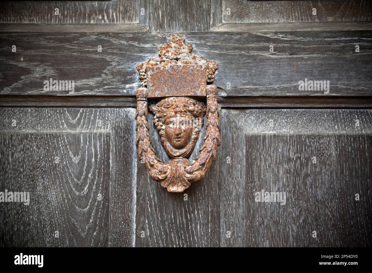 Old vintage door knocker on a weather worn door, classical style Stock Photo