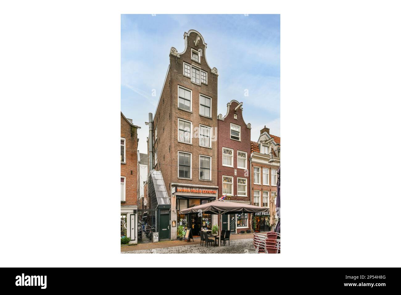 Amsterdam, Netherlands - 10 April, 2021: an old building with a clock on it's side and people walking in the street next to each other buildings Stock Photo