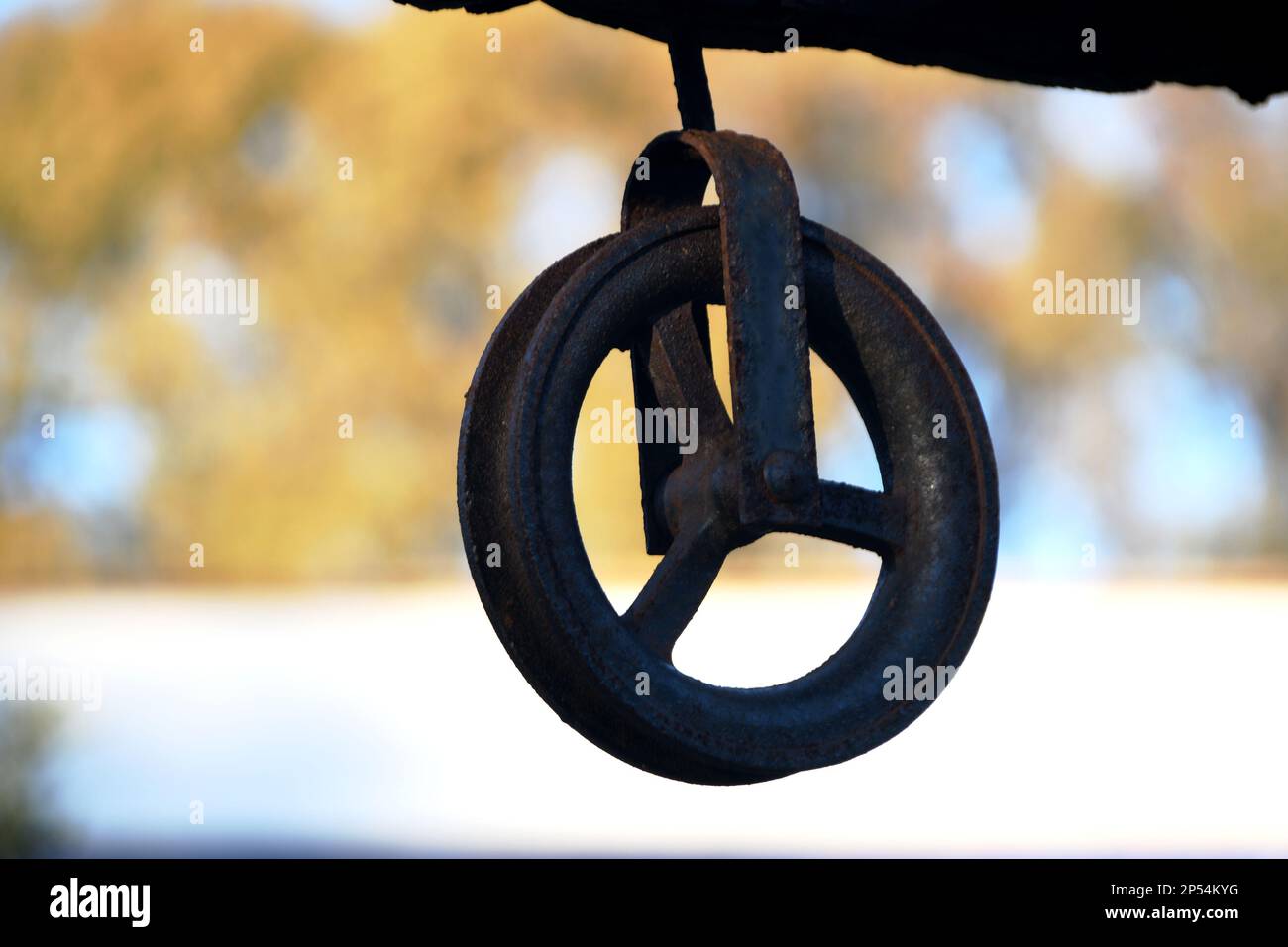 Old iron pulley to draw water from a well with a bucket and rope Stock