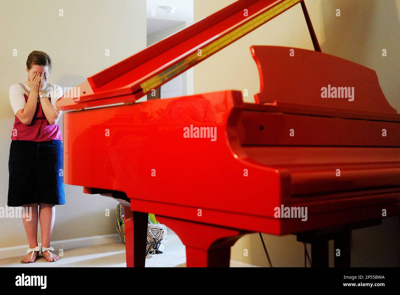 Bridgett Adams, 16, holds her head in her hands after being surprised with  a custom made, Ferrari Red baby grand piano Friday, Aug. 30, 2013 in Cape  Girardeau, Mo. Adams, who is