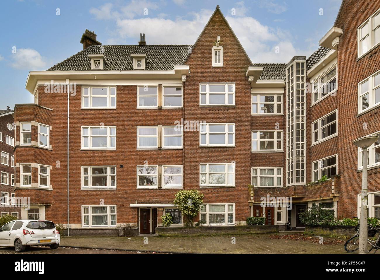an apartment building with cars parked in the driveway and two bicycles ...