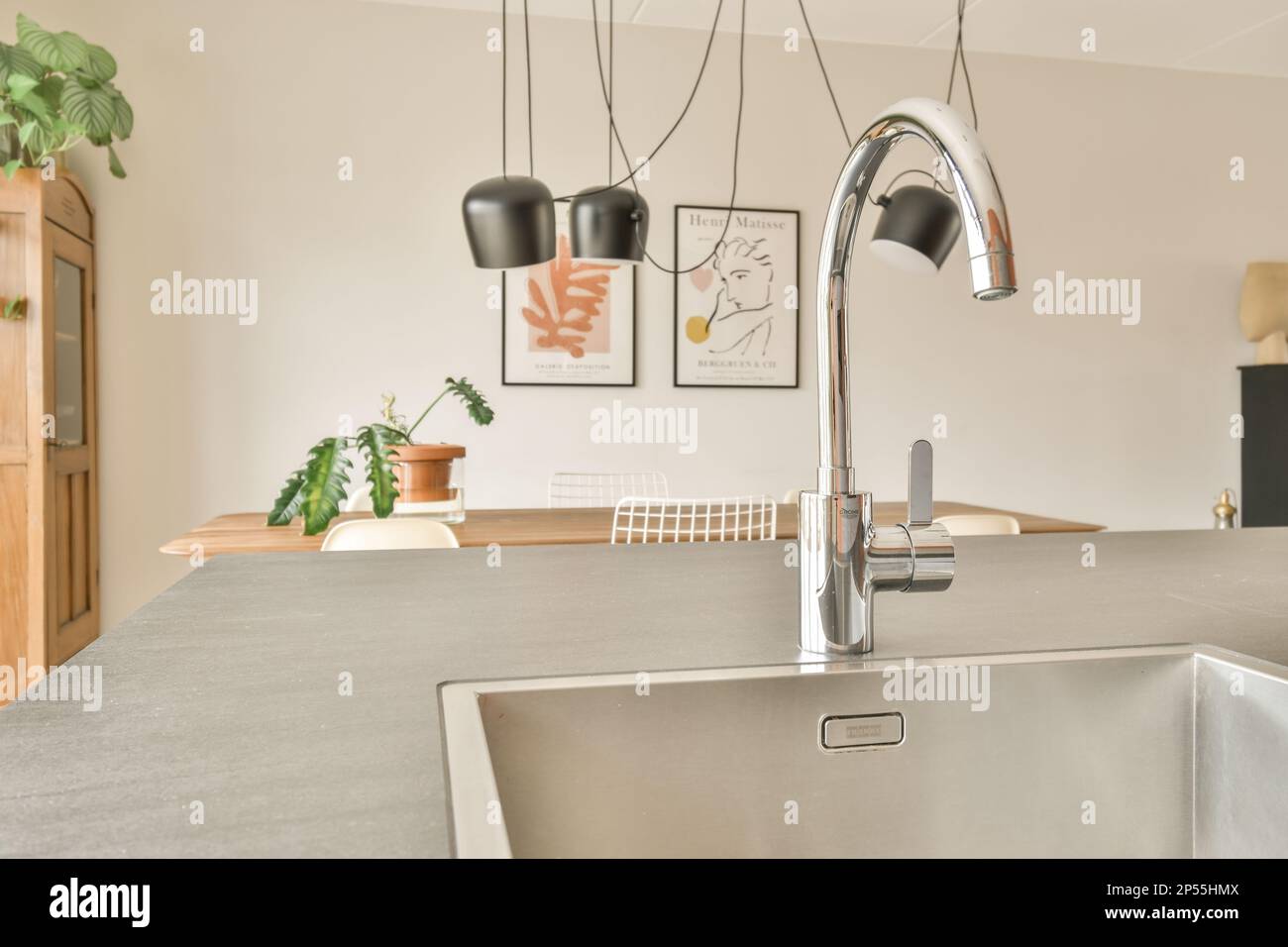 a modern kitchen with an island sink and stainless steel fauced fae in the center of the room Stock Photo