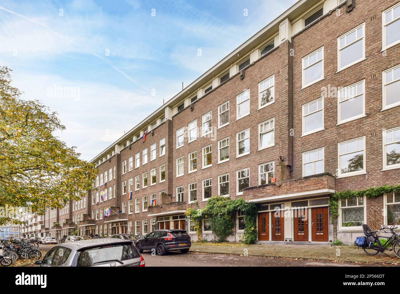 a brick apartment building with cars parked on the street next to it ...