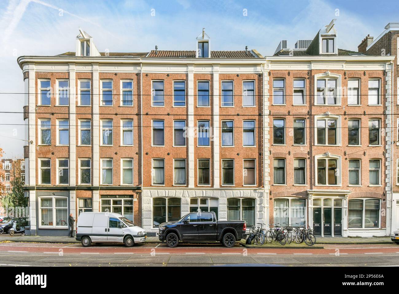an apartment building with cars parked on the street next to it and two ...