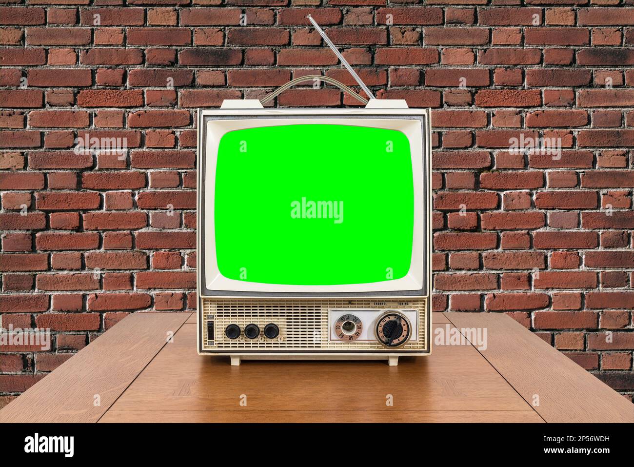 Vntage portable television with wood table, brick wall and chroma key green screen. Stock Photo