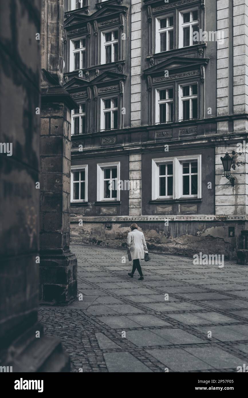 woman at the old town square with tenement house in the background Stock Photo
