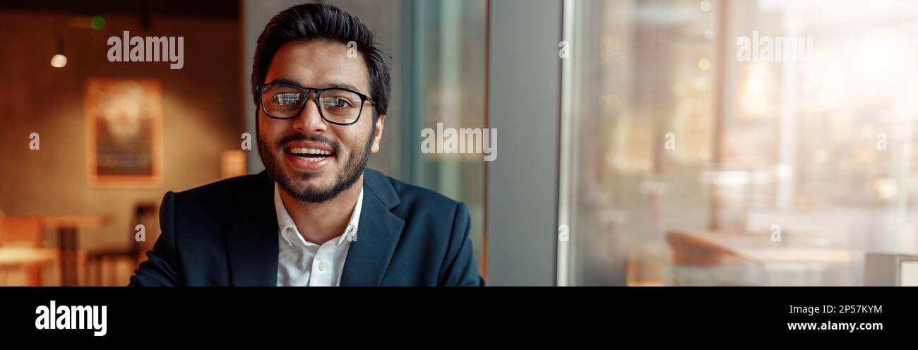 Smiling businessman working with graphs and charts at modern cafe. Blurred background Stock Photo