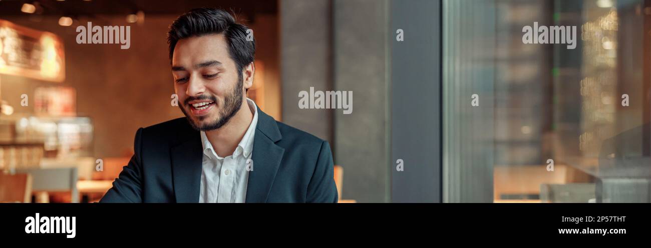 Smiling businessman working with graphs and charts at modern cafe Stock Photo