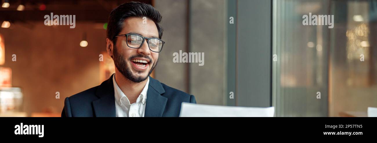 Smiling indian businessman drinking coffee and working with documents in cafe Stock Photo