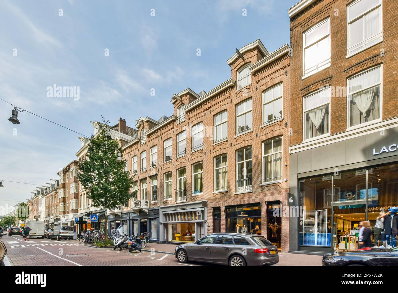 a city street with cars parked on the side and people walking down the ...