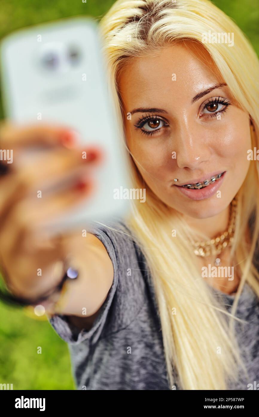 Vertical portrait of young blond woman in selfie position. Fixes the