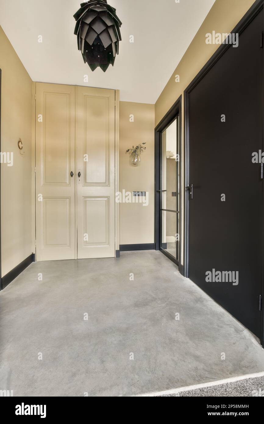 an empty room with two black doors and a light fixture hanging from the